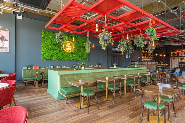 The Green room seating area with planting and neon sign