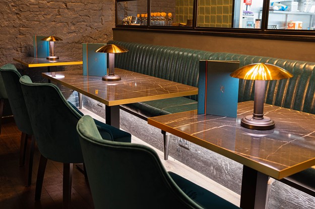 teal fixed seating next to marble effect tables with table lamps