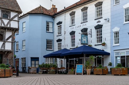 Blue pub in the centre of Axbridge with umbrellas outside 